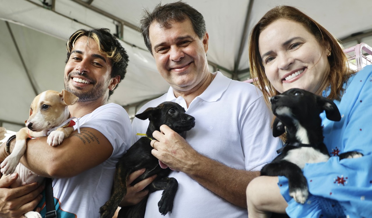 secretário Apolo, prefeito Evandro e primeira-dama Cristiane posam com filhotes de cachorro no colo